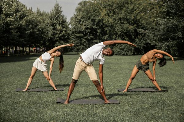 Diverse group of people practicing yoga outdoors, enjoying fresh air.